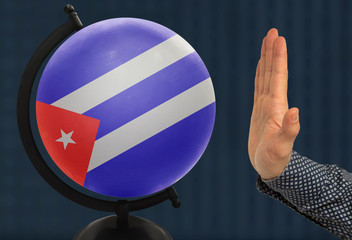 gesture of a male hand warns against the globe, which depicts a colored national state flag Cuba