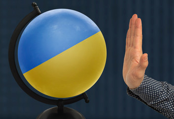 gesture of a male hand warns against the globe, which depicts a colored national state flag Ukraine