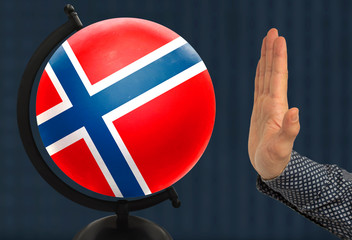 gesture of a male hand warns against the globe, which depicts a colored national state flag Norway