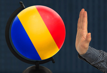 The warning gesture of a man’s hand refers to a globe with a colored national state flag romania
