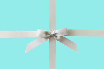 Silver ribbon with a bow as a gift on a mint background