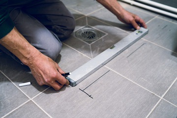 Construction worker craftsman measuring tiles on the floor before installation of the glass tile protective wall equipment
