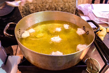 typical Italian fried fritters in a pot with oil.
