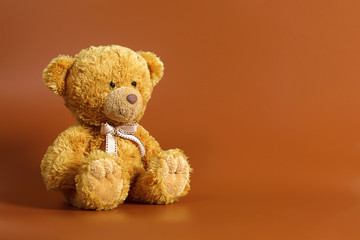 Soft warm cute brown teddy bear on color background. Isolated. Soft brown coffee background. Copy space for text.