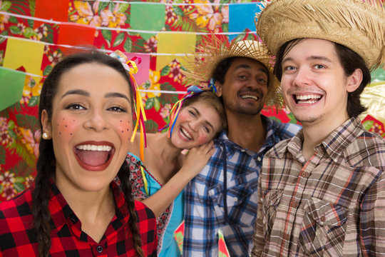 June Party: Festa Junina. Young people in traditional plaid clothes at holiday festival. Decoration of flags in background.