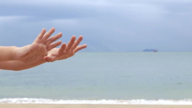 a child pouring sand from hand at the beach