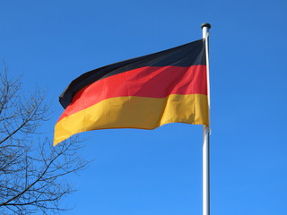 Germany flag bold and proud floating in the wind, against sunny blue sky