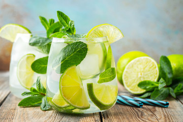 Two Mojito cocktail with ice cubes in a glass on a rustic table, selective focus