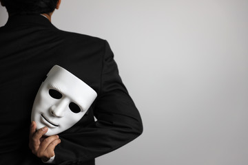 politician or businessman wearing black suit and hiding white mask