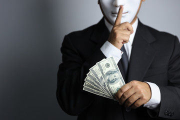 politician or businessman wearing black suit and white mask show banknotes as a promise of buying...
