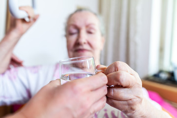 A young woman gives a glass of water to an old woman