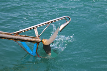 The boat propellers spinning in the sea water from the diesel engine. long tail boat