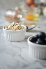 Organic rolled oats in bowl, on marble table. Concept of cooking ingredients, decorate bakery, healthy eating and nutrition.