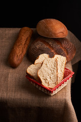 Bakery - gold rustic crusty loaves of bread and buns on black chalkboard background. Still life captured from above