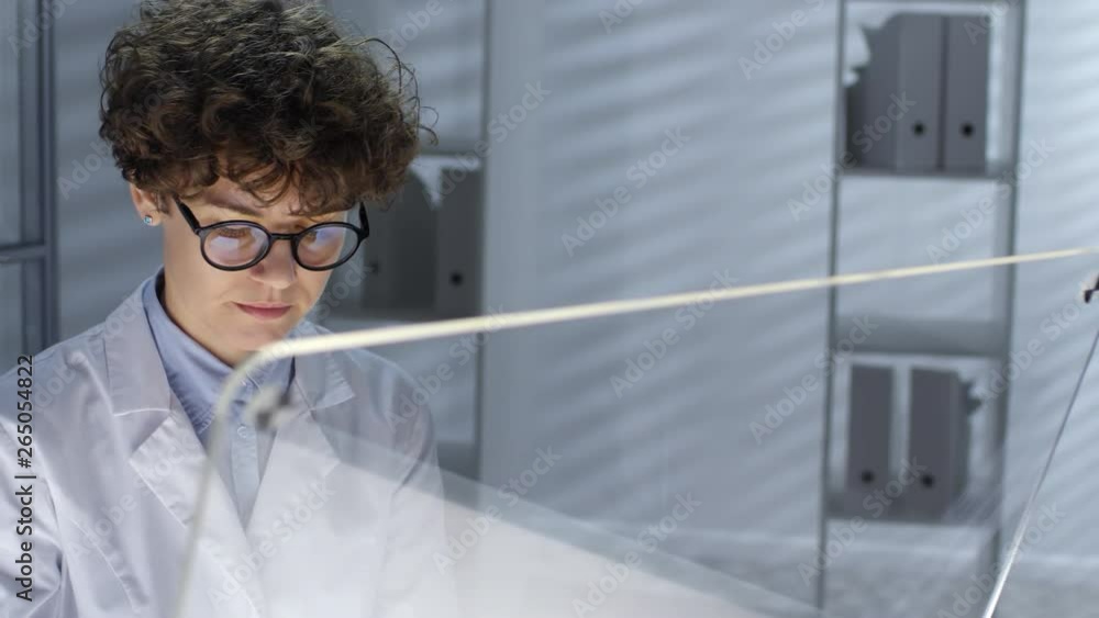 Poster female doctor in glasses and lab coat working on futuristic computer with transparent monitor. video