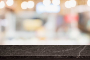 Empty black marble stone table top and blurred bokeh cafe and restaurent interior background with vintage filter - can used for display or montage your products.