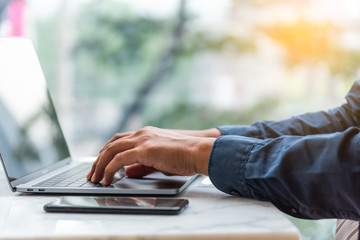 Hands of business man typing keyboard laptop computer. Male working on laptop in a cafe.