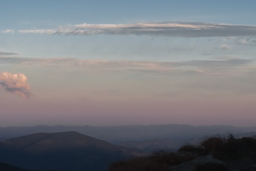 The mountains on a sunny day and sunset with clouds and coniferous forest. Landscape