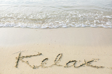Handwritten on a sandy beach. Relax spelled on a sandy beach.
