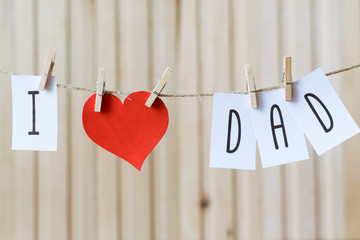 Fathers day message with paper heart hanging with pins over light wooden board. Happy Birthday