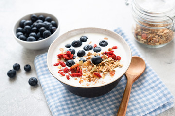 Yogurt bowl with granola, goji berries and blueberry on a blue checkered textile. Healthy breakfast...