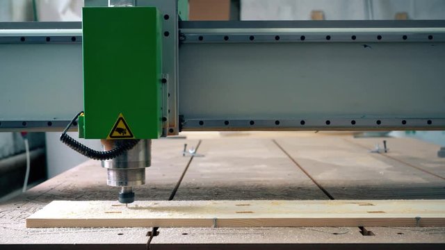 Engraving machine carving wood with help of person