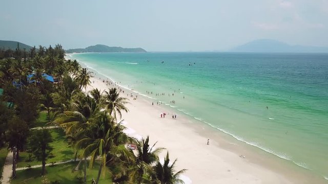 Natural Doc Let beach white sand paradise coastal blue clear water sea ocean waves. Tall coconut palm landscape seascape horizon. Vietnam relax hotels resorts lot people tourists walk. Aerial forward