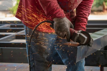 Close-up view of cutting steel shape, huge amount of sparks. Angle grinder sparks angle grinder cutting steel. Cutting steel with angle grinder. Worker cutting metal