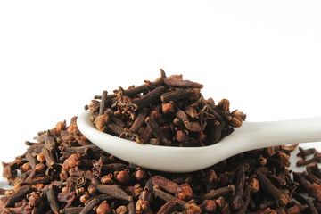 dried spice clove aromatic flower buds in spoon on white background