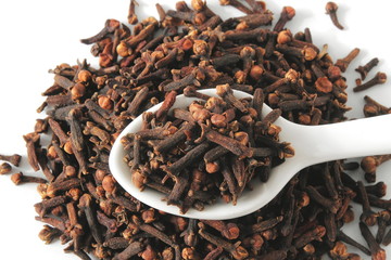 dried spice clove aromatic flower buds in spoon on white background