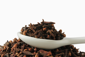 dried spice clove aromatic flower buds in spoon on white background