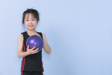 Asian girl  holding purple gymnastic ball and smiles to camera. Concept for sport and healthy activity for modern kid..