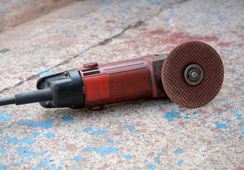 Angle grinder with rotary blade on a Cement floor surface. Electric grinder machine on the floor