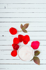 moisturizer and rose petals on white wood