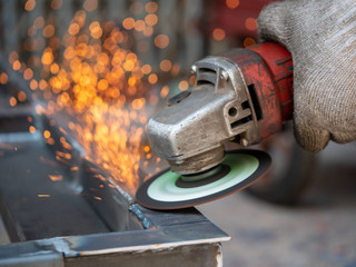 Close-up view of cutting steel shape, huge amount of sparks. Angle grinder sparks angle grinder cutting steel. Cutting steel with angle grinder. Worker cutting metal