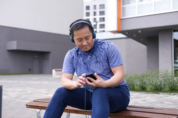 Korean man stretches against the background of the city. Healthy lifestyle. Adult man  practicing yoga in nature.