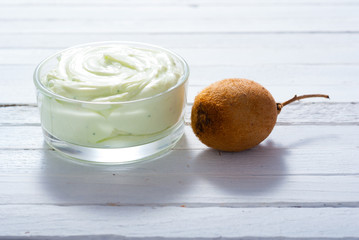 moisturizer cream with kiwi on white wooden table