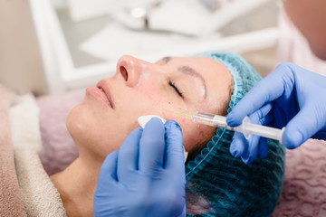 Closeup of cosmetologist hands making facial lifting injection for woman