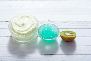 moisturizer and anti aging gel with kiwi on white wooden table