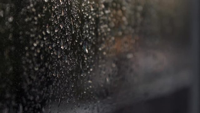 The lights of the night city. Misted glass. Liquid raindrops on the window. Defocused auto traffic lights at sunset day. Sadness and sad mood background.