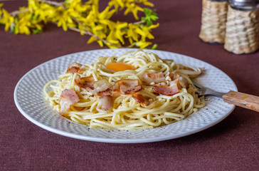 Pasta Carbonara. Flowers in the background. Italian food.