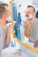 Guy shaving his beard in bathroom