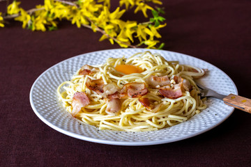Pasta Carbonara. Flowers in the background. Italian food.