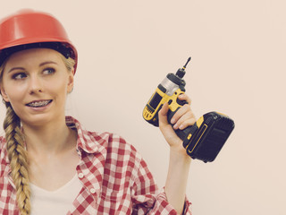 Woman wearing helmet using drill