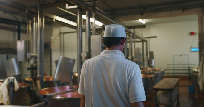 Slow motion of a cheesemaker is supervising production of Parmesan cheese using fresh and biologic milk following the ancient Italian tradition in dairy factory.