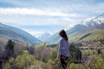 Young girl on the background of spring mountains. Beautiful mountain gorge. Nature and adventure.