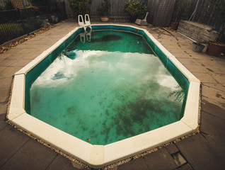 Neglected swimming pool with green algae
