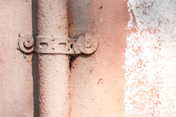 A screw with a washer attaches a tube to the pink wall