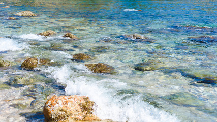 background of transparent sea water and bottom, with stones and waves