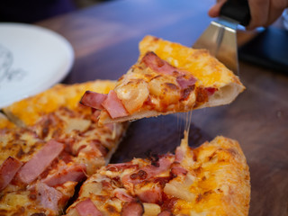 Hot pizza slice with melting cheese on a rustic wooden table.